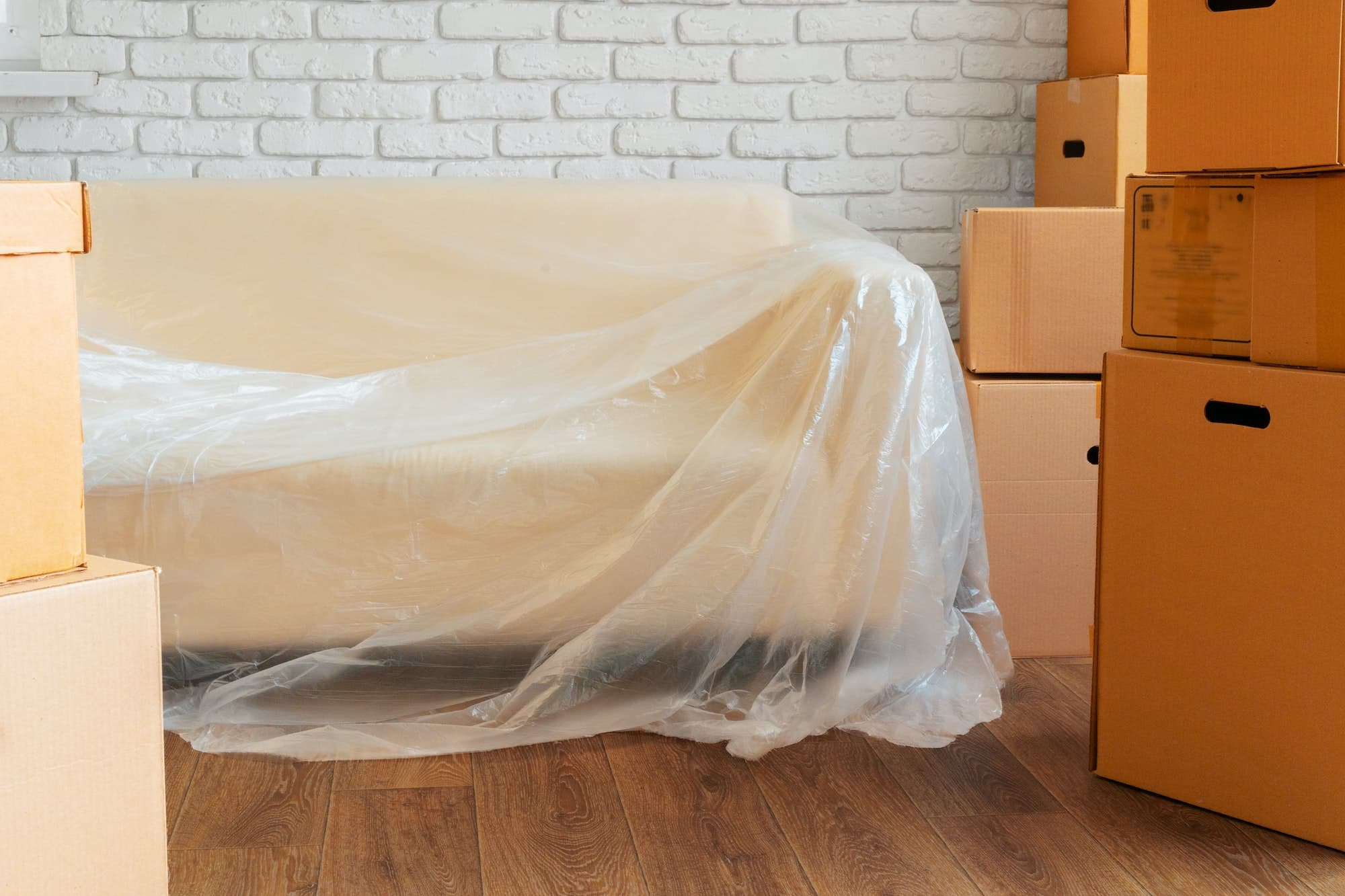 Packed sofa and stack of cardboard boxes in a room. Moving concept
