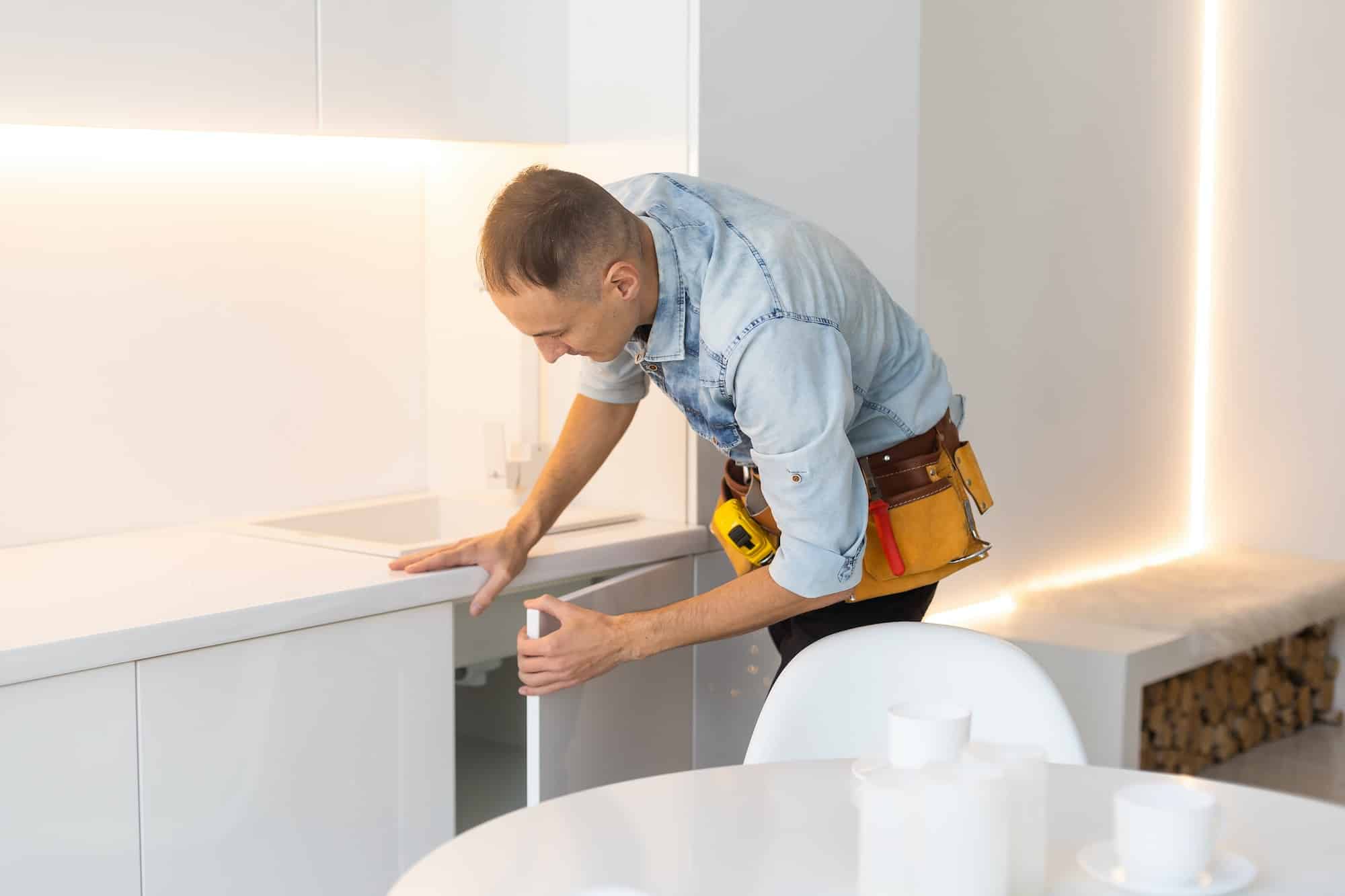 kitchen installation. Worker assembling furniture.