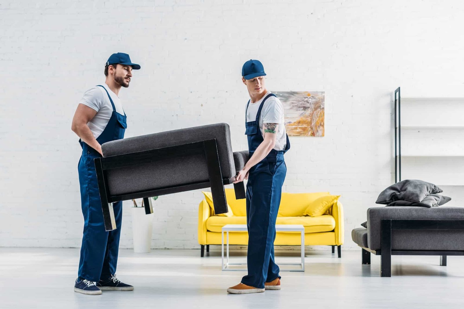 two movers in uniform transporting furniture in apartment